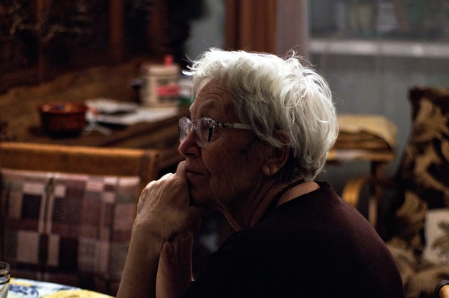 Symbolbild: Ältere Dame sitzt nachdenklich am Tisch